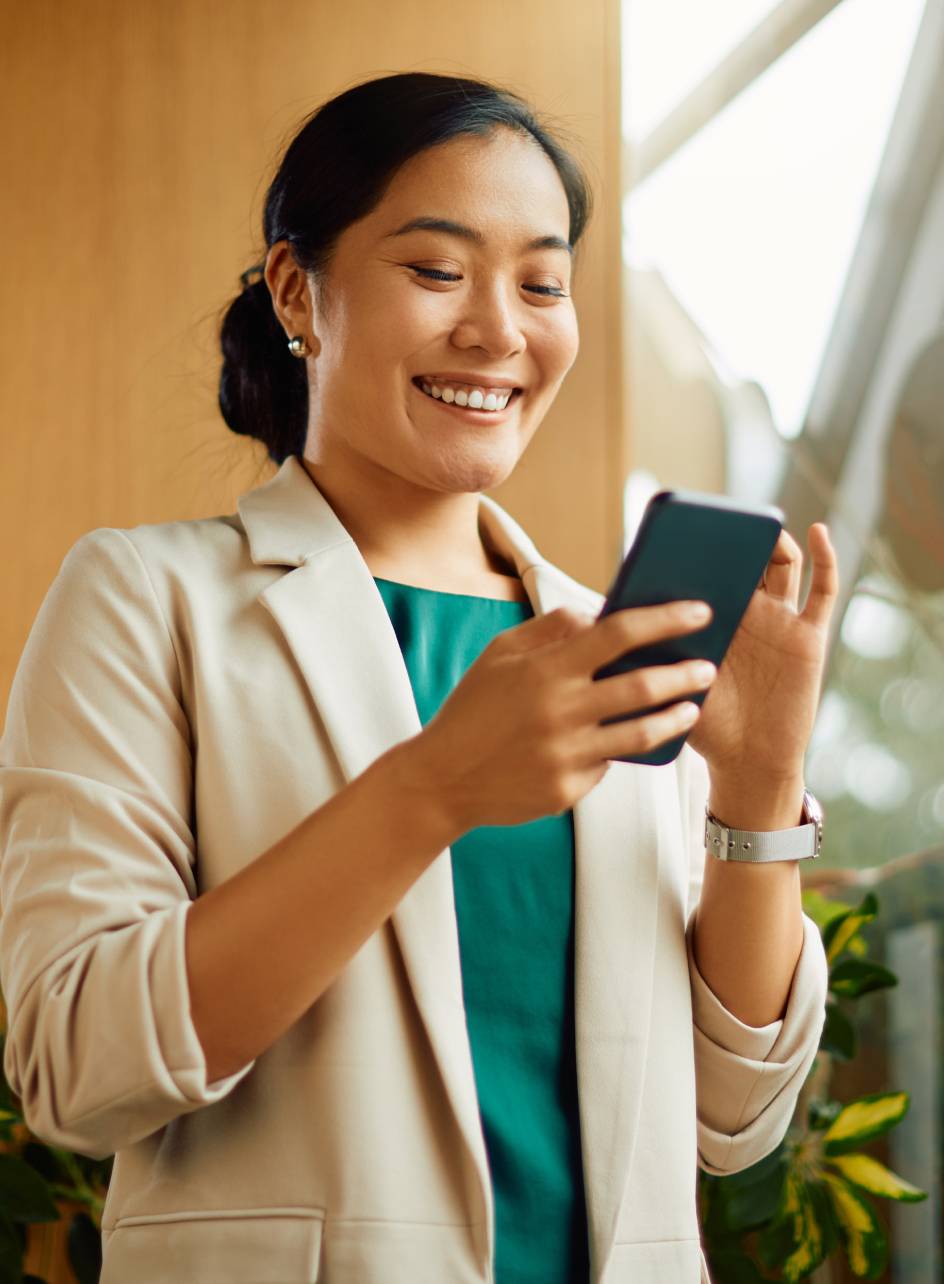Mulher segurando um celular sorrindo enquanto olha para a tela dele.